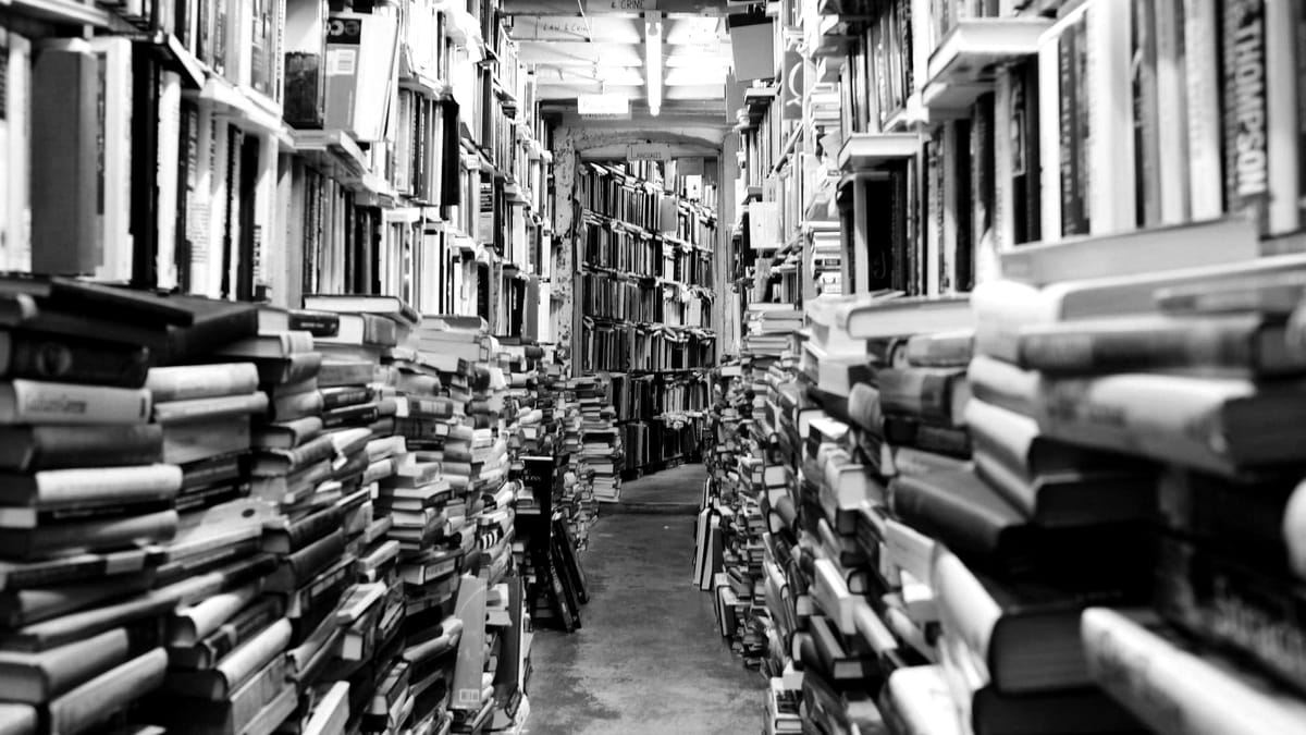 A narrow aisle of books and bookshelves in a library or bookstore.